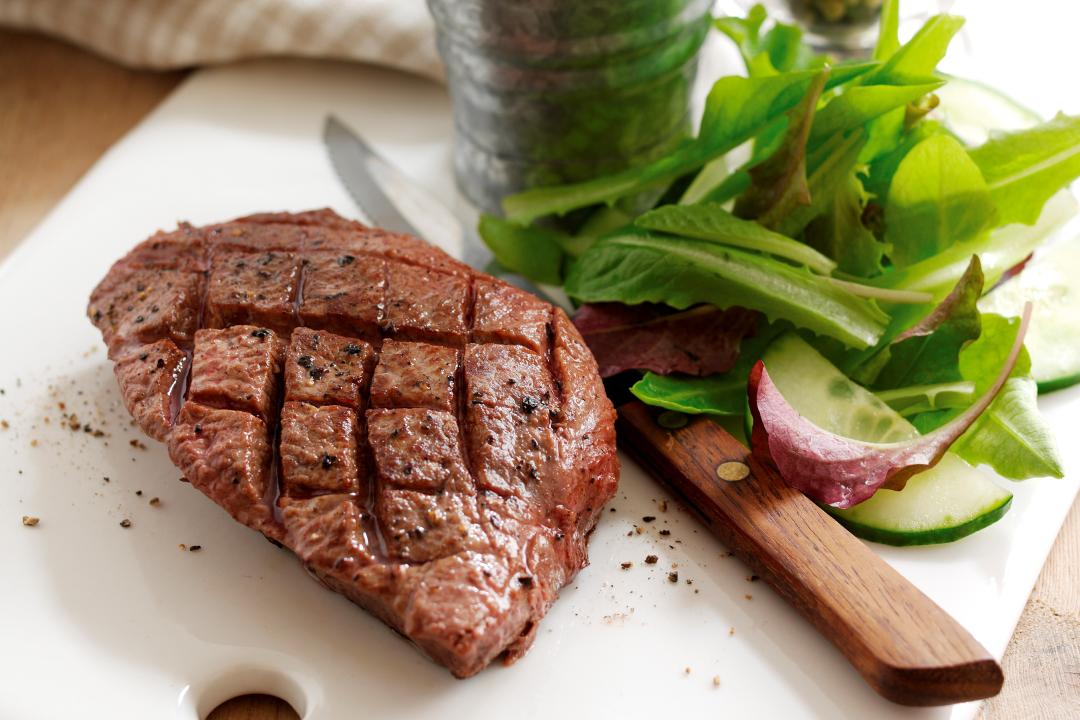 cooked flat iron steak served with salad
