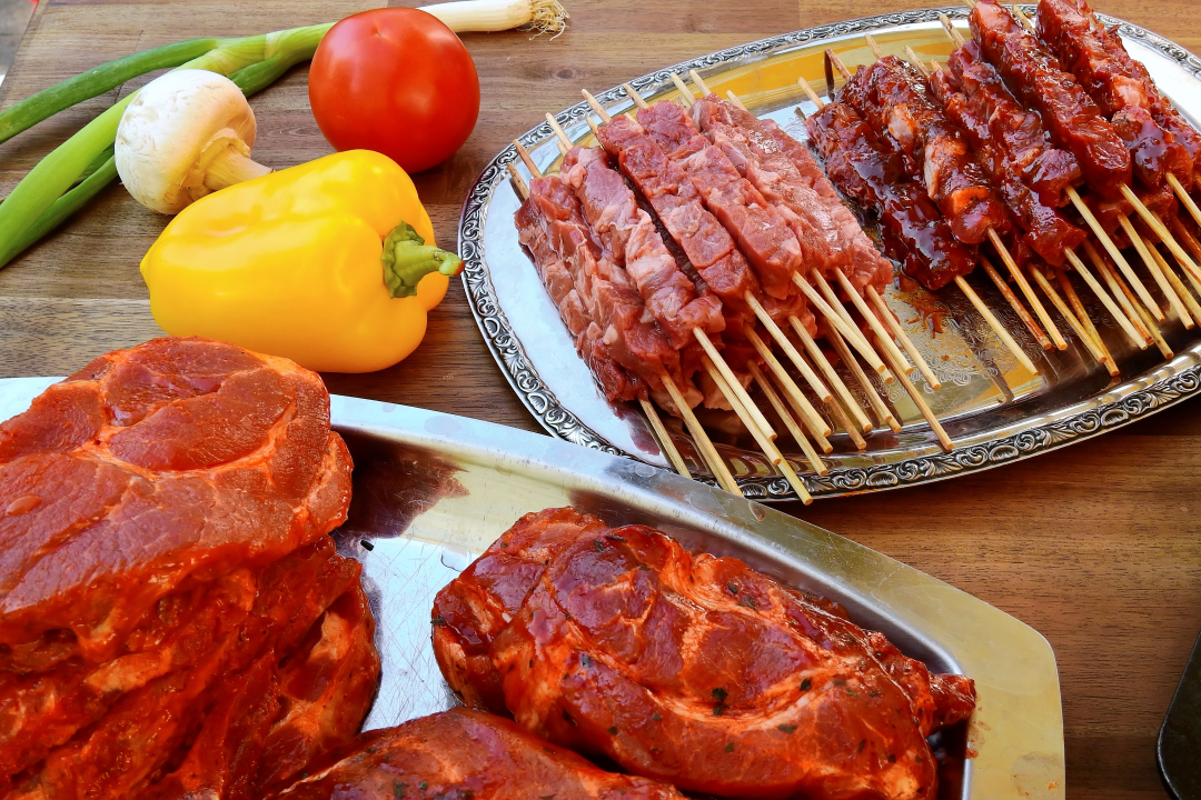 marinated lamb steaks and marinated chicken kebabs on silver plates on a wooden table