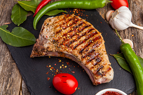 grilled pork loin chop displayed on a slate with garnish
