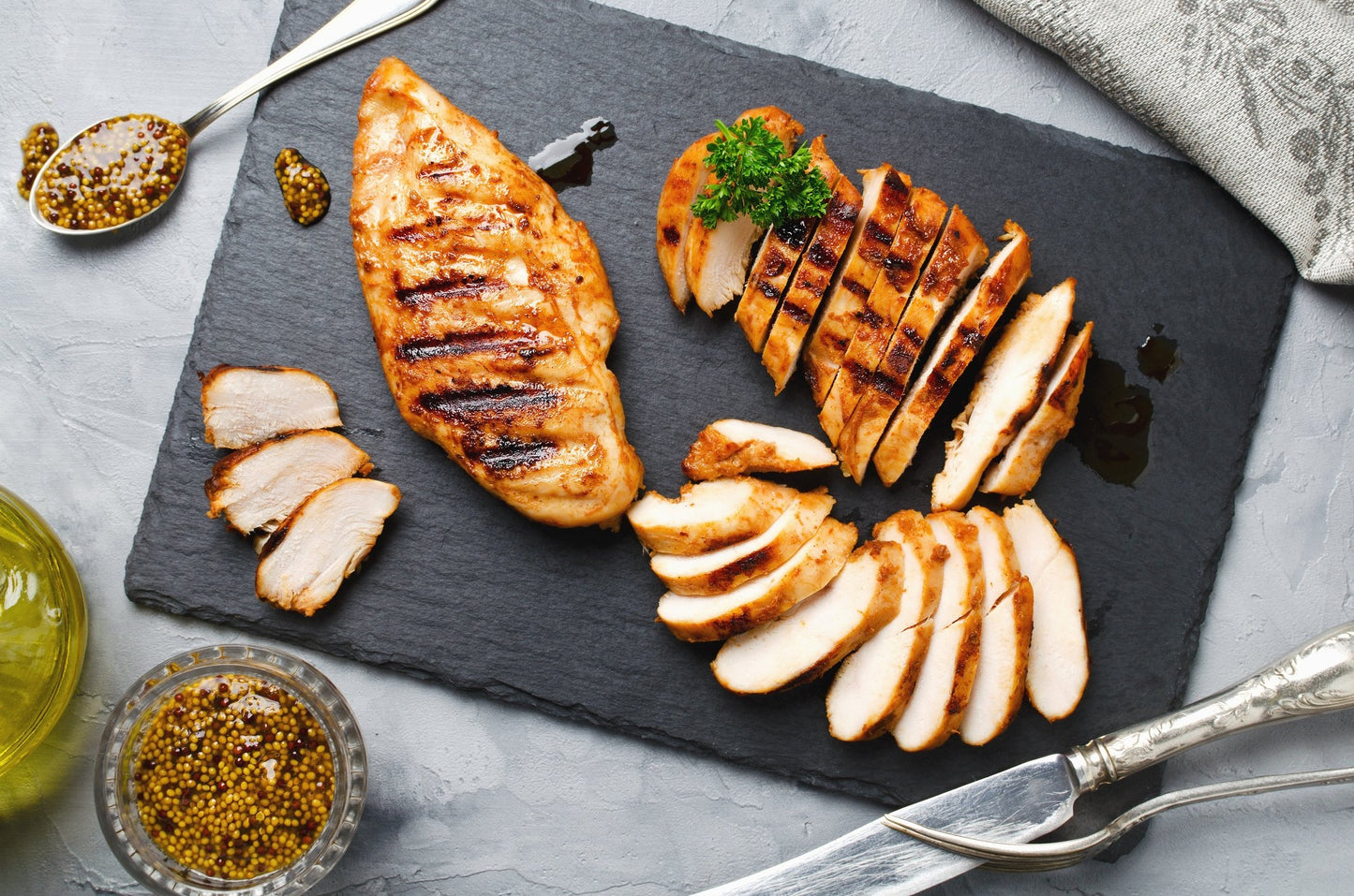 2 cooked chicken fillets displayed on a slate with seasonings