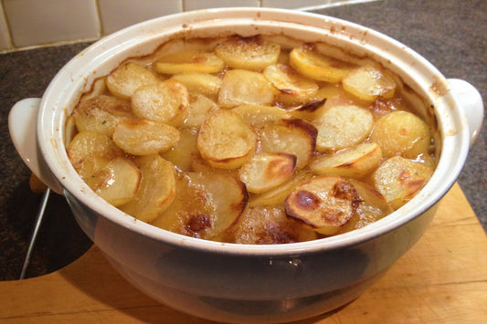 lamb hotpot in a large casserole dish with sliced potatoes on top