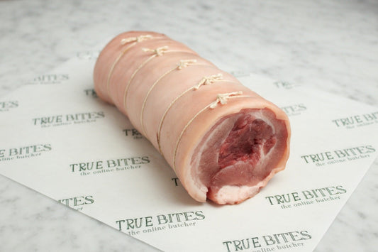 raw boneless rolled pork belly on greaseproof paper
