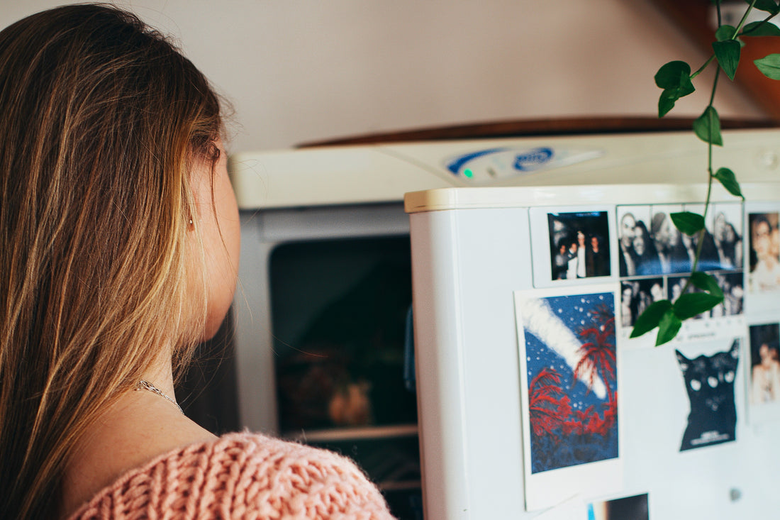 woman in pink knitted jumper looking in fridge