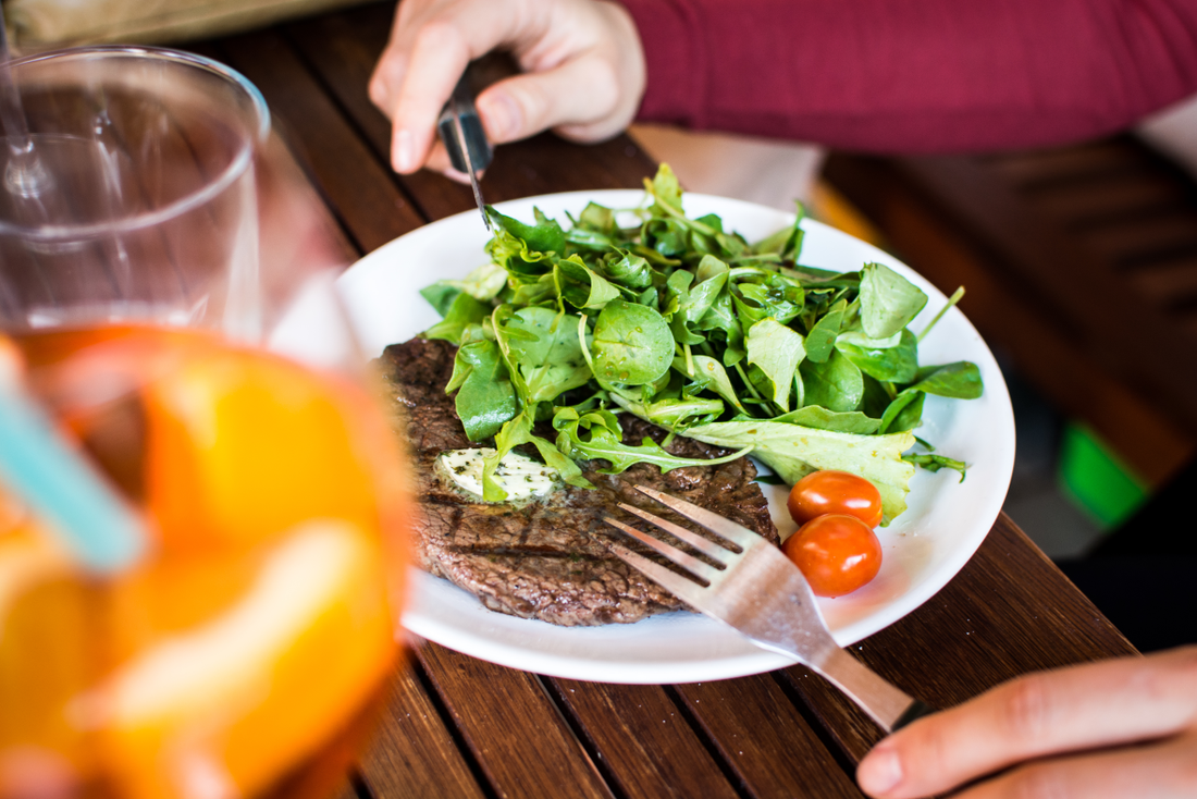 barbecued beef steak on a white plate served with green salad
