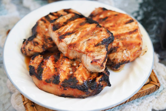 4 grilled pork chops piled on a white plate