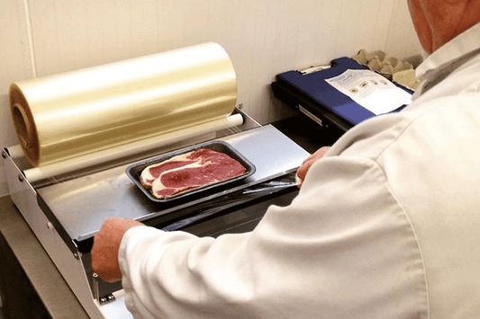 butcher in white coat wrapping steak