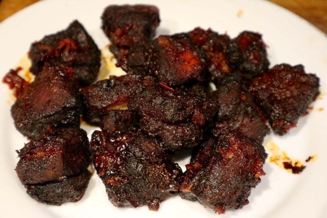 cooked pork belly burnt ends on a white plate