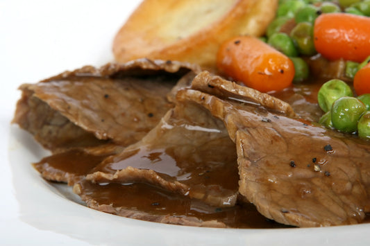 sliced roast beef on a plate with gravy and Yorkshire puddings