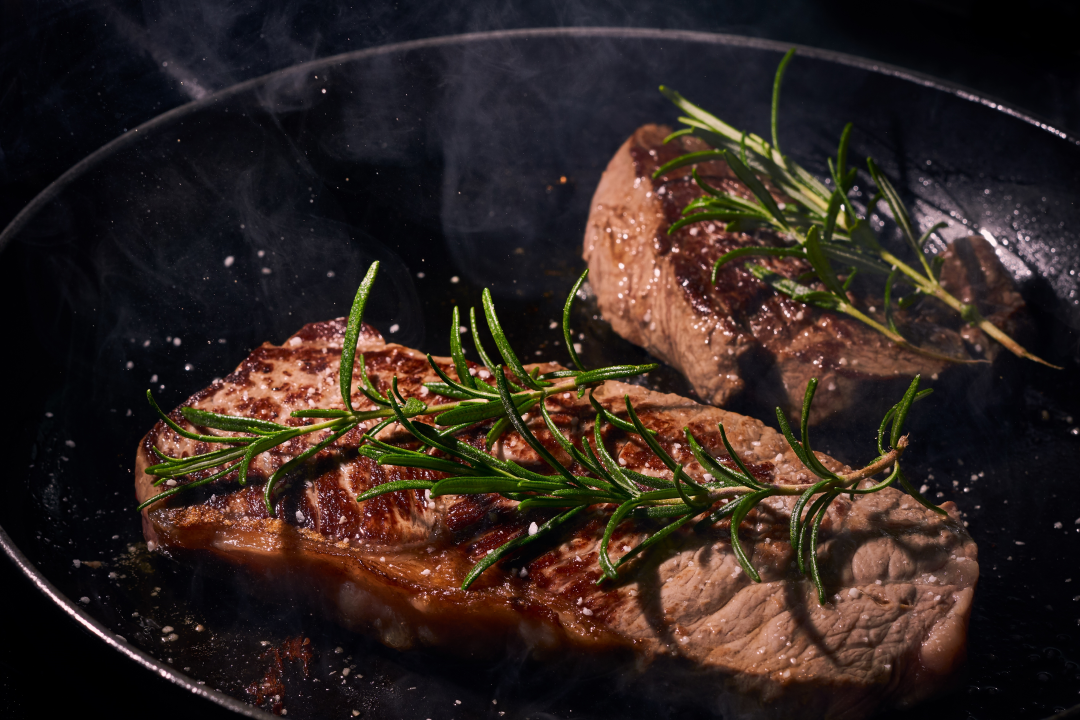 two sirloin steaks cooking in a pan