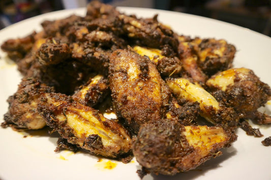 a pile of jerk chicken wings on a white plate