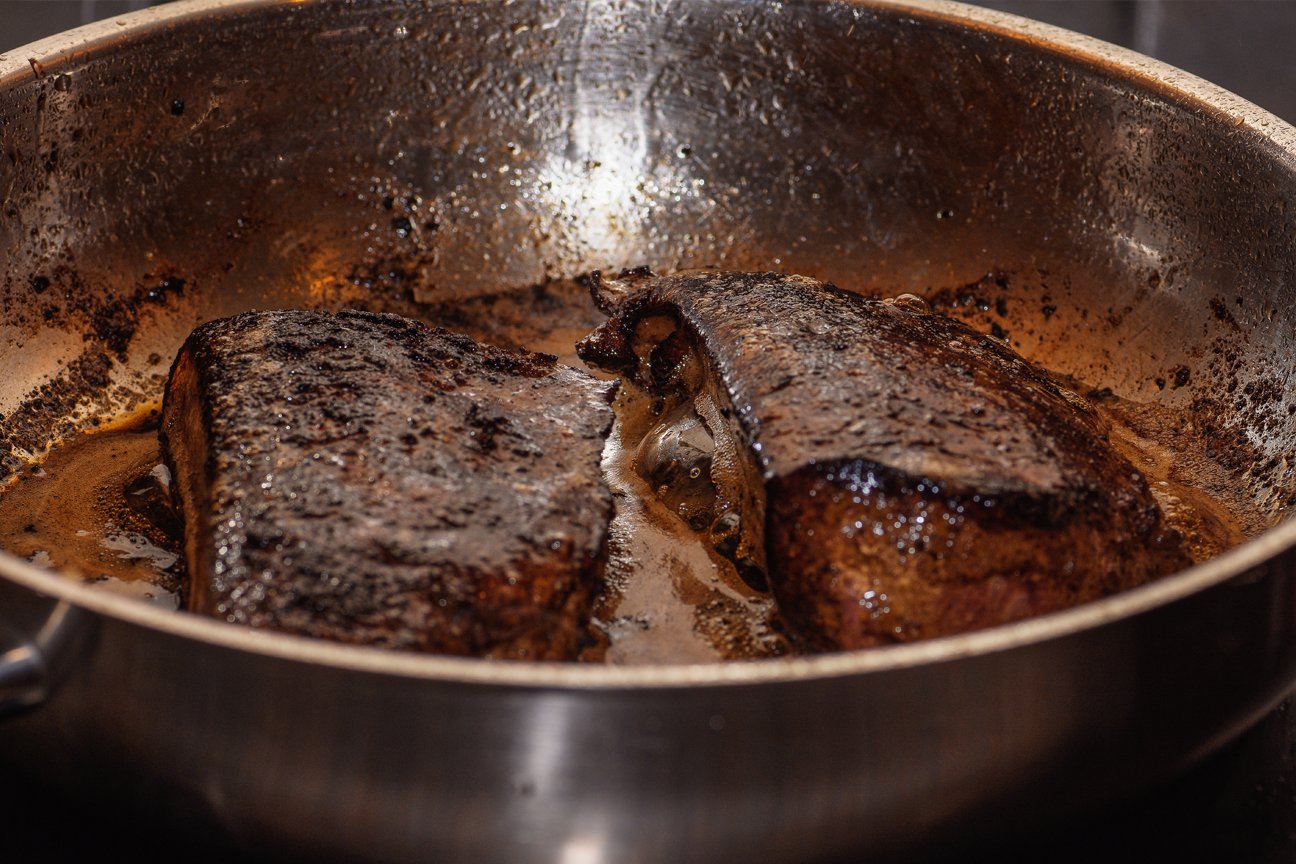 liver being fried in a stainless steel pan