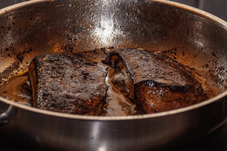 liver being fried in a stainless steel pan