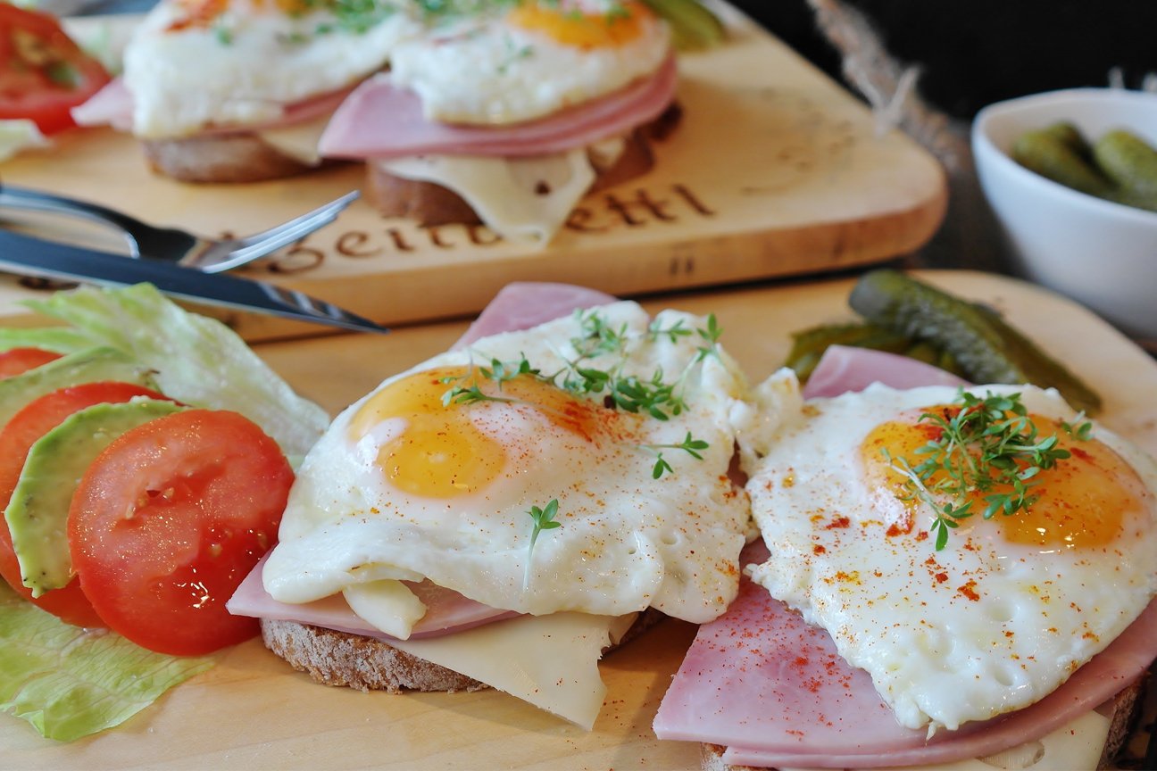 cooked ham topped with friends eggs and serve with a salad on a wooden board