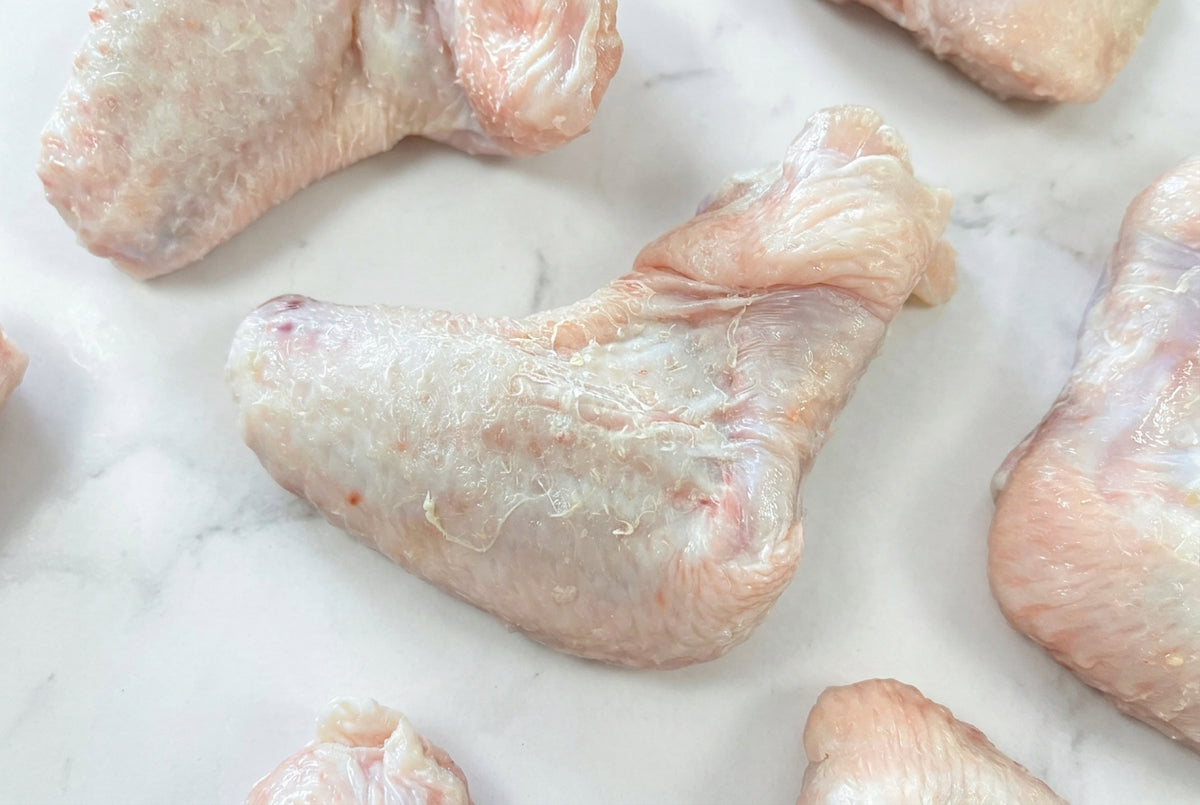 Close up of raw 2 joint chicken wing on a dark wooden surface