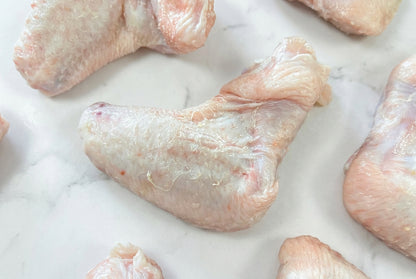 Close up of raw 2 joint chicken wing on a dark wooden surface