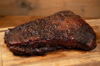 smoked flat beef brisket on a wooden cutting board 