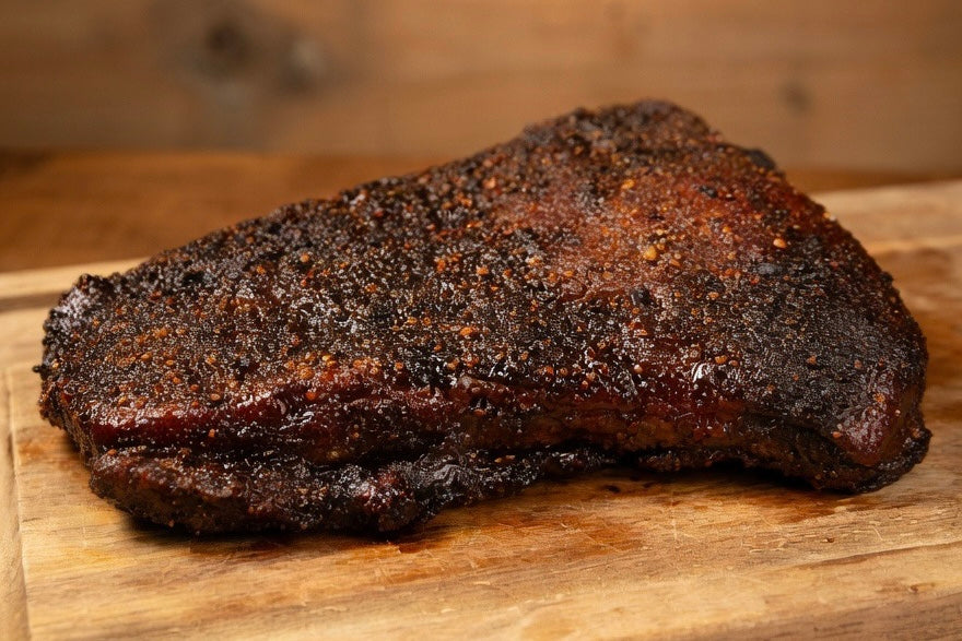 smoked flat beef brisket on a wooden cutting board 