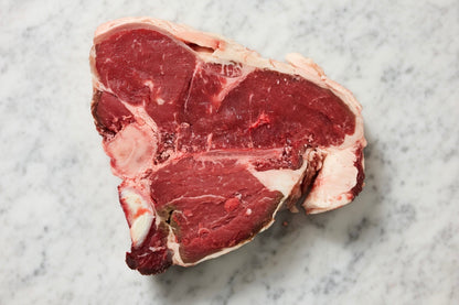 Raw beef t-bone steak on a marble surface