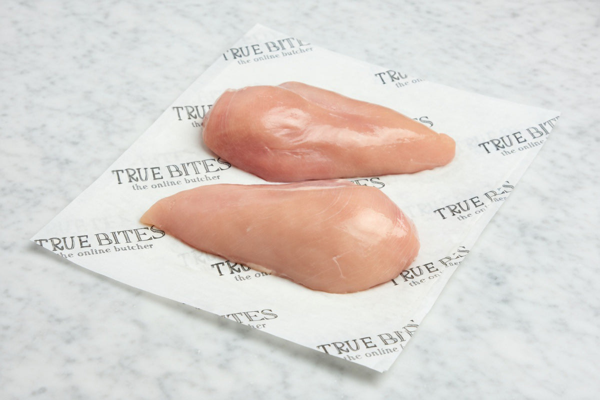 Two pieces of chicken breast on a 'True Bites' branded paper with a textured background.