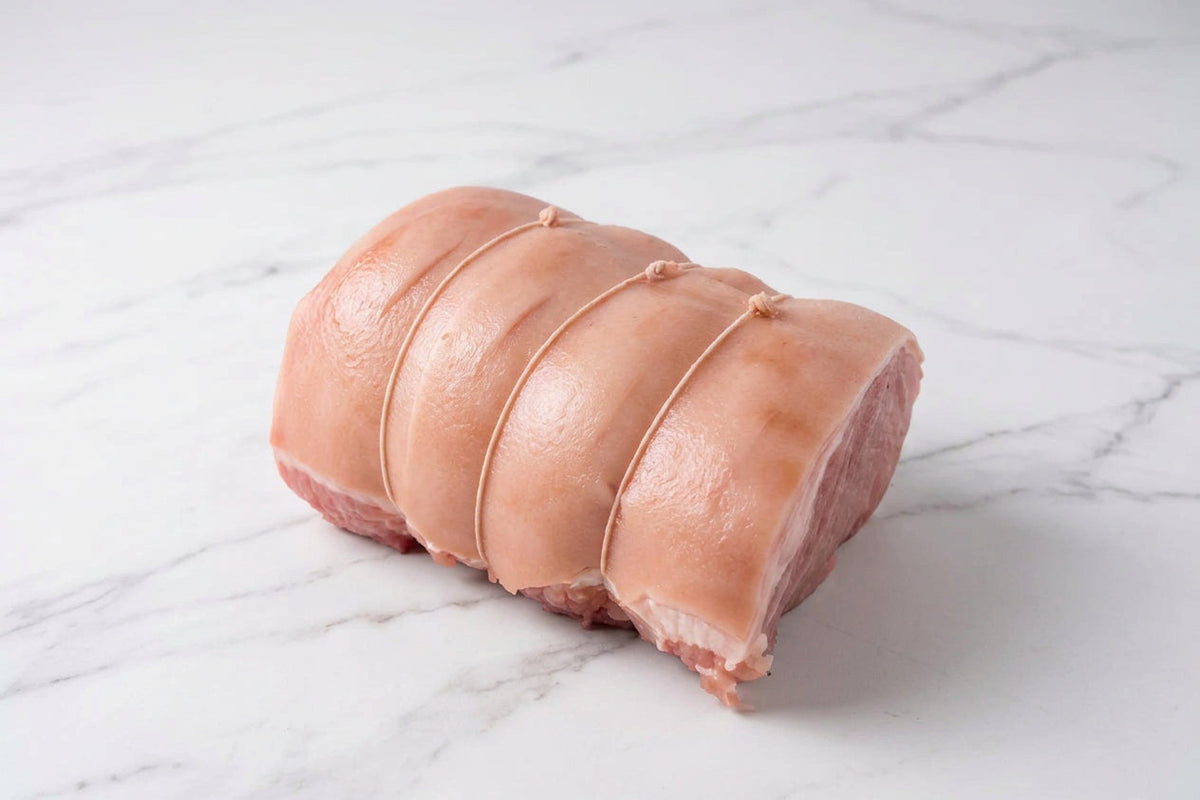 A raw, tied corner gammon roast with rind  on a white countertop.