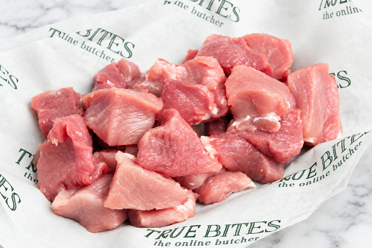 Raw diced pork placed on branded butcher paper that reads True Bites the online butcher.
