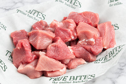 Raw diced pork placed on branded butcher paper that reads True Bites the online butcher.