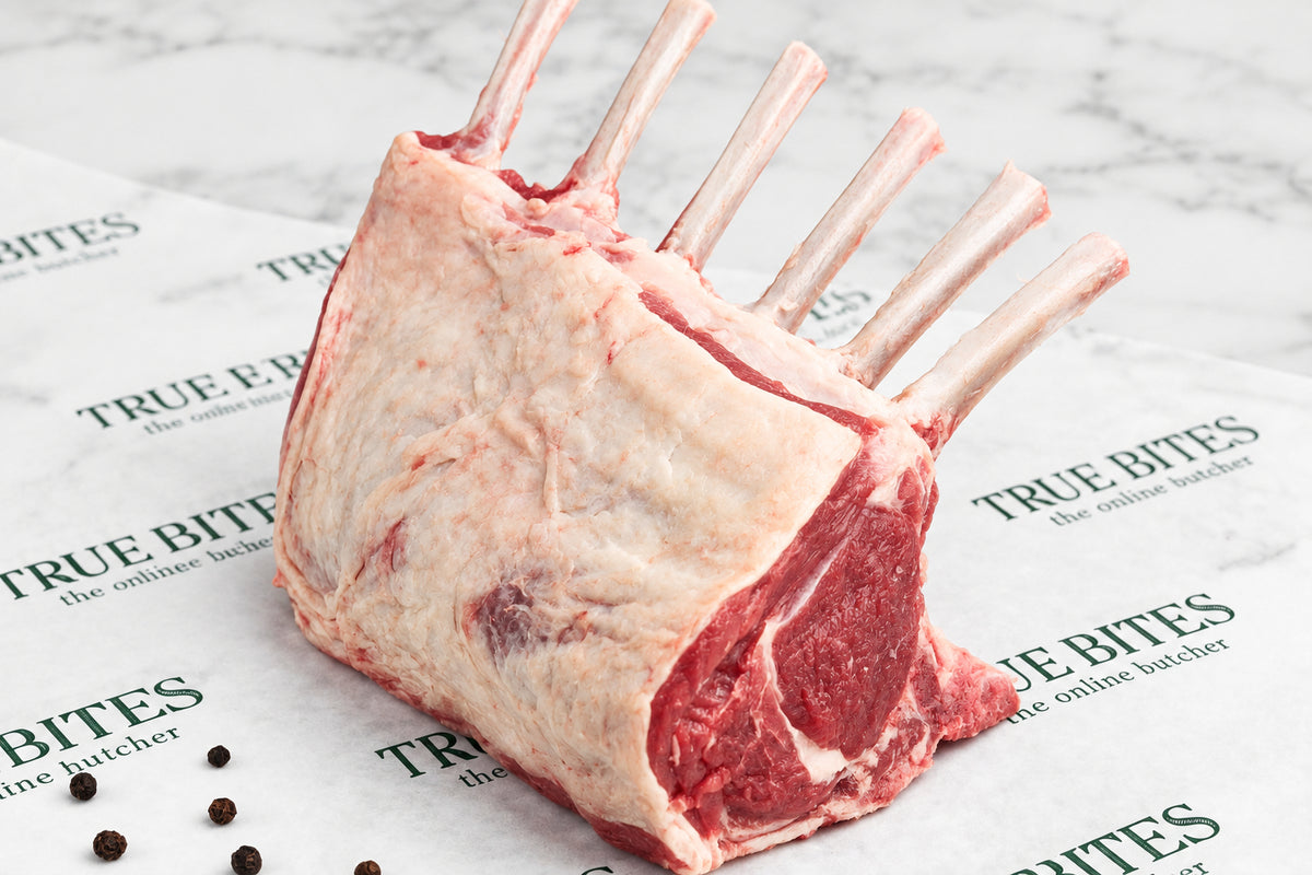 raw French trimmed 6 bone rack of lamb on branded true bites butcher paper