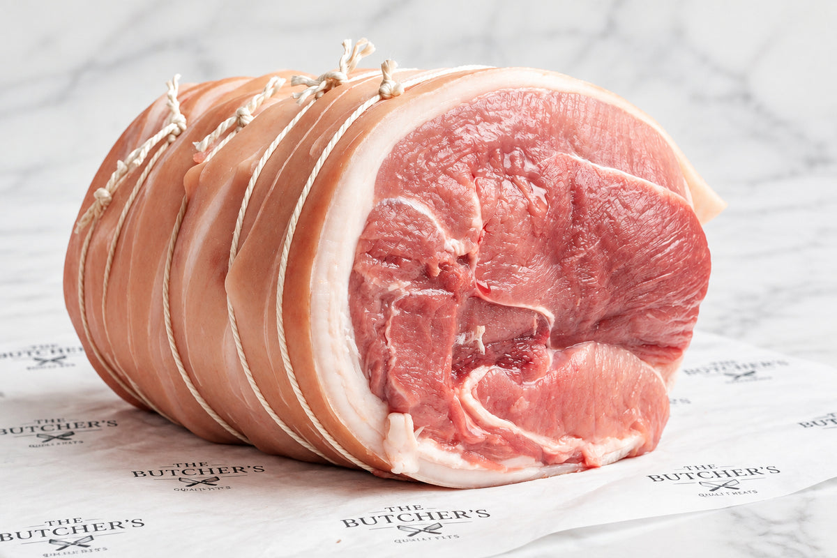 A large, raw, boneless pork shoulder on white butcher paper, set against a dark, blurred background.
