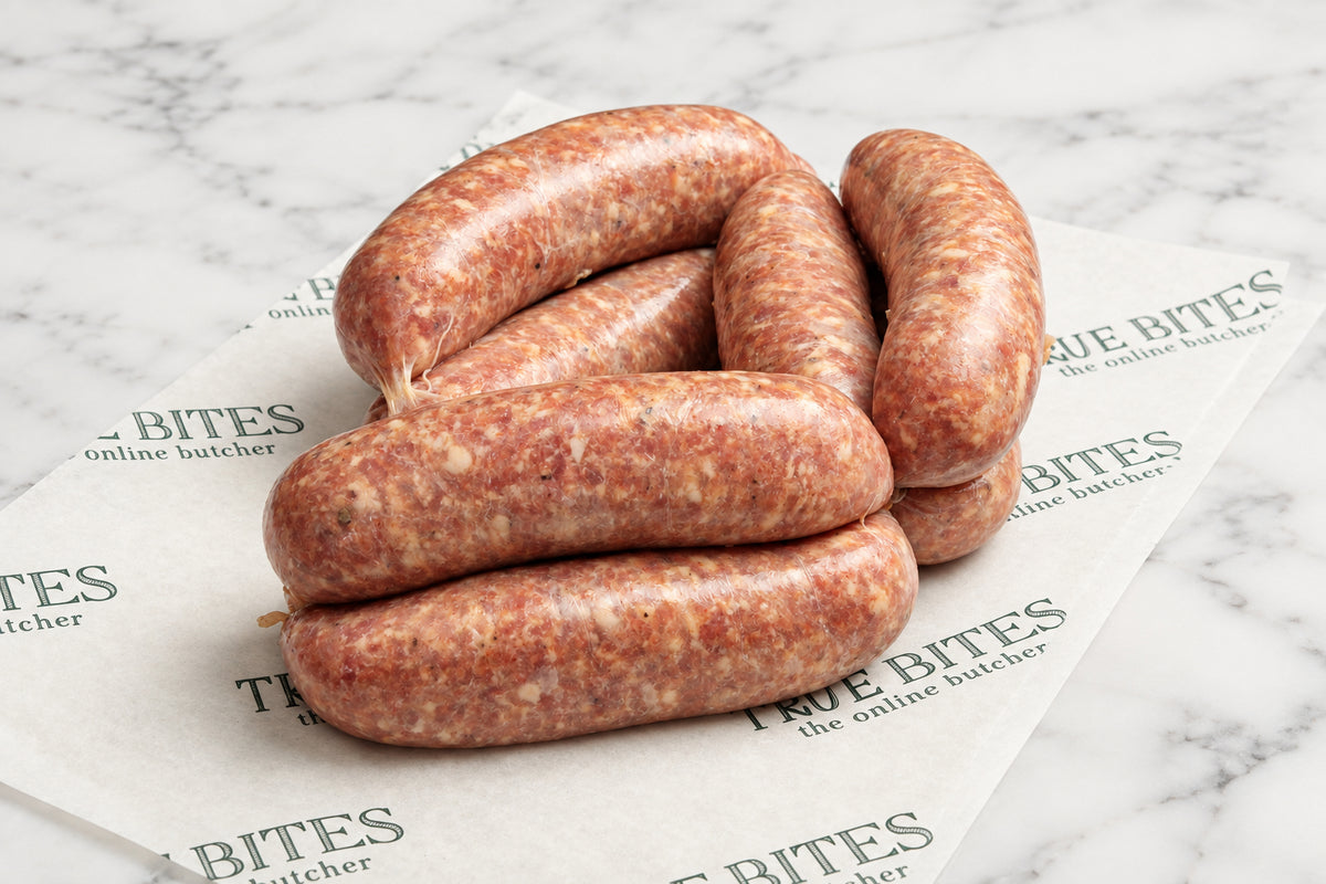 A coiled bundle of raw sausage links resting on branded butcher paper over a dark wooden surface.