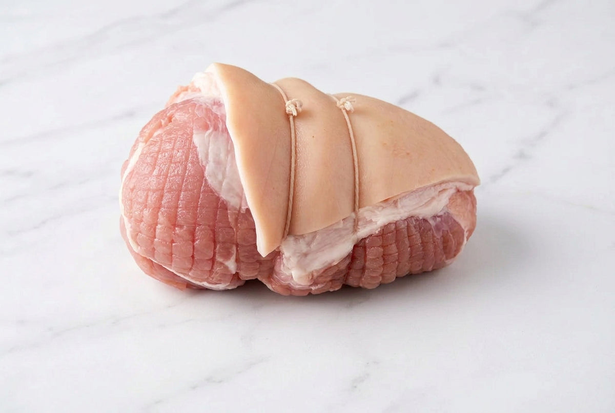 A close-up of a raw gammon slipper  with rind on top on a marble surface.