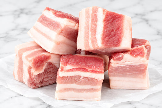 raw large pork belly cubes on wooden counter top.