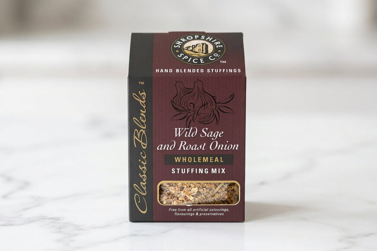 A box of Hand Blended Stuffings Classic Blends 'Wild Sage and Roast Onion' Wholemeal Stuffing Mix on a white tabletop with a blurred indoor background.