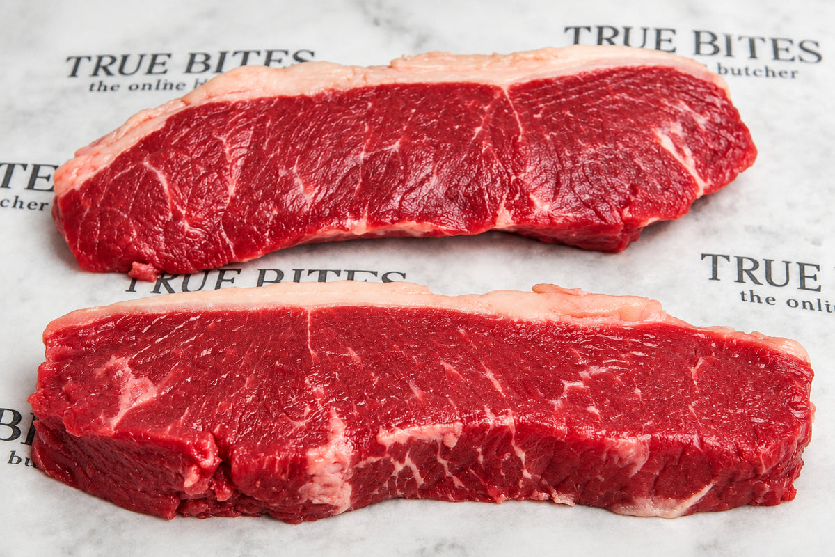Two raw beef sirloin steaks with visible marbling, placed on a branded butcher paper background.