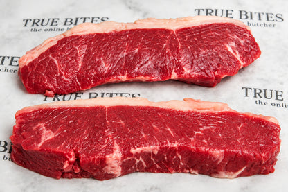 Two raw beef sirloin steaks with visible marbling, placed on a branded butcher paper background.