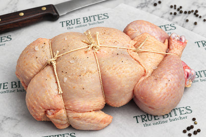 A whole spatchcock chicken tied with butcher's string, placed on branded butcher paper reading 'TRUE BITES the online butcher' with a knife visible at the top left.