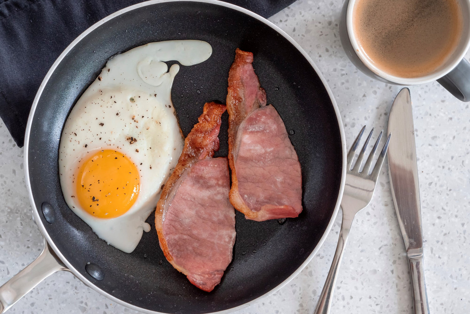 back bacon frying in a pan with an egg