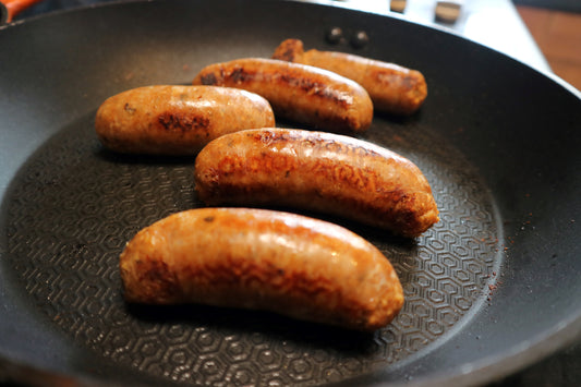 cooked jerk chicken sausages in a frying pan