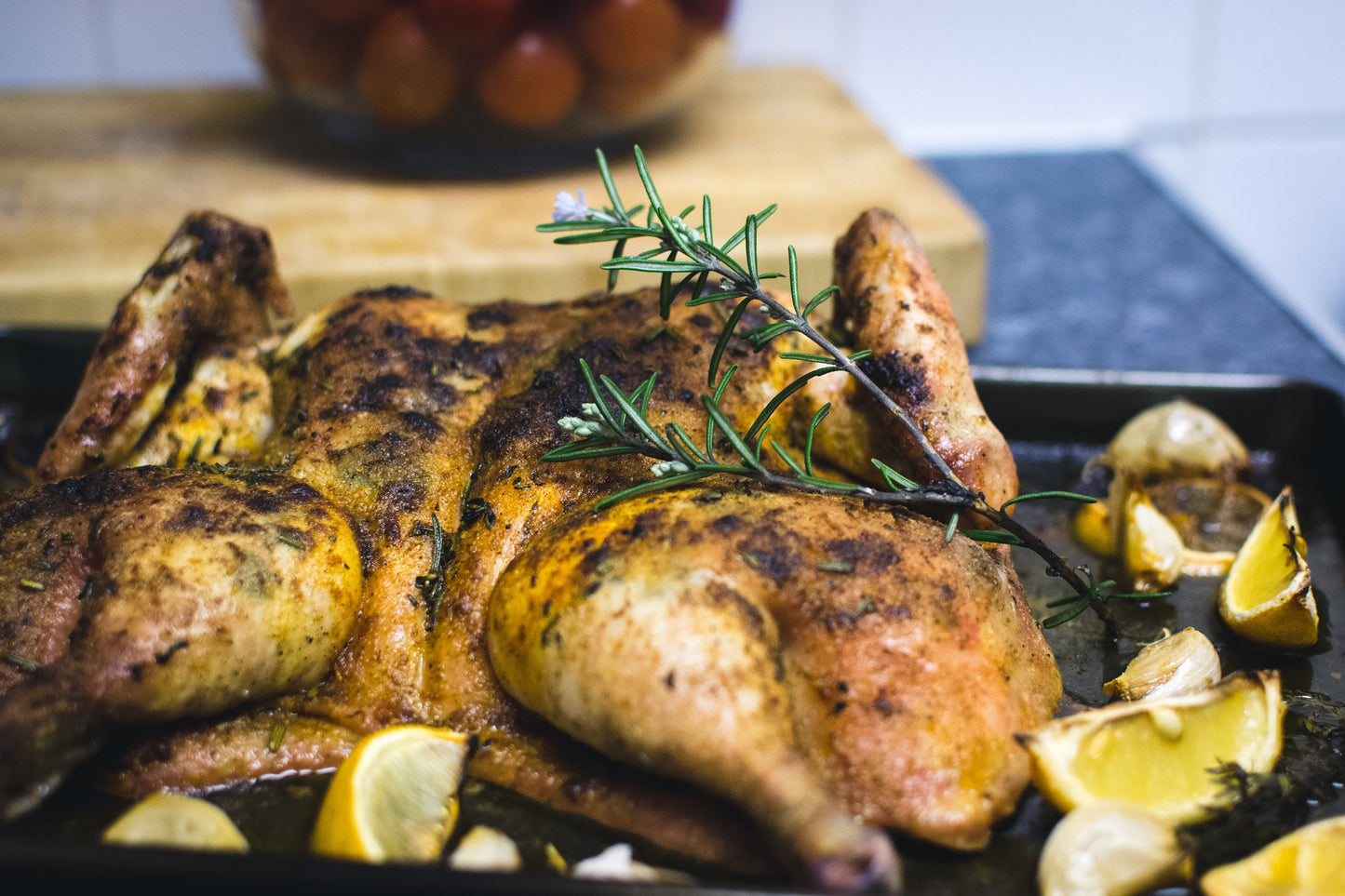 cooked spatchcock chicken on a roasting dish with lemon