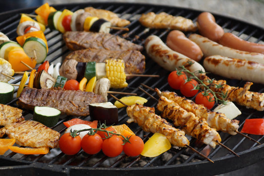 various bbq meats cooking on a charcoal barbecue