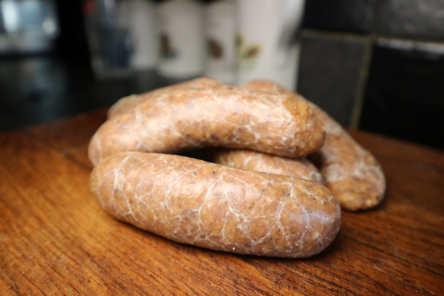 raw jerk chicken sausage on a wooden chopping board