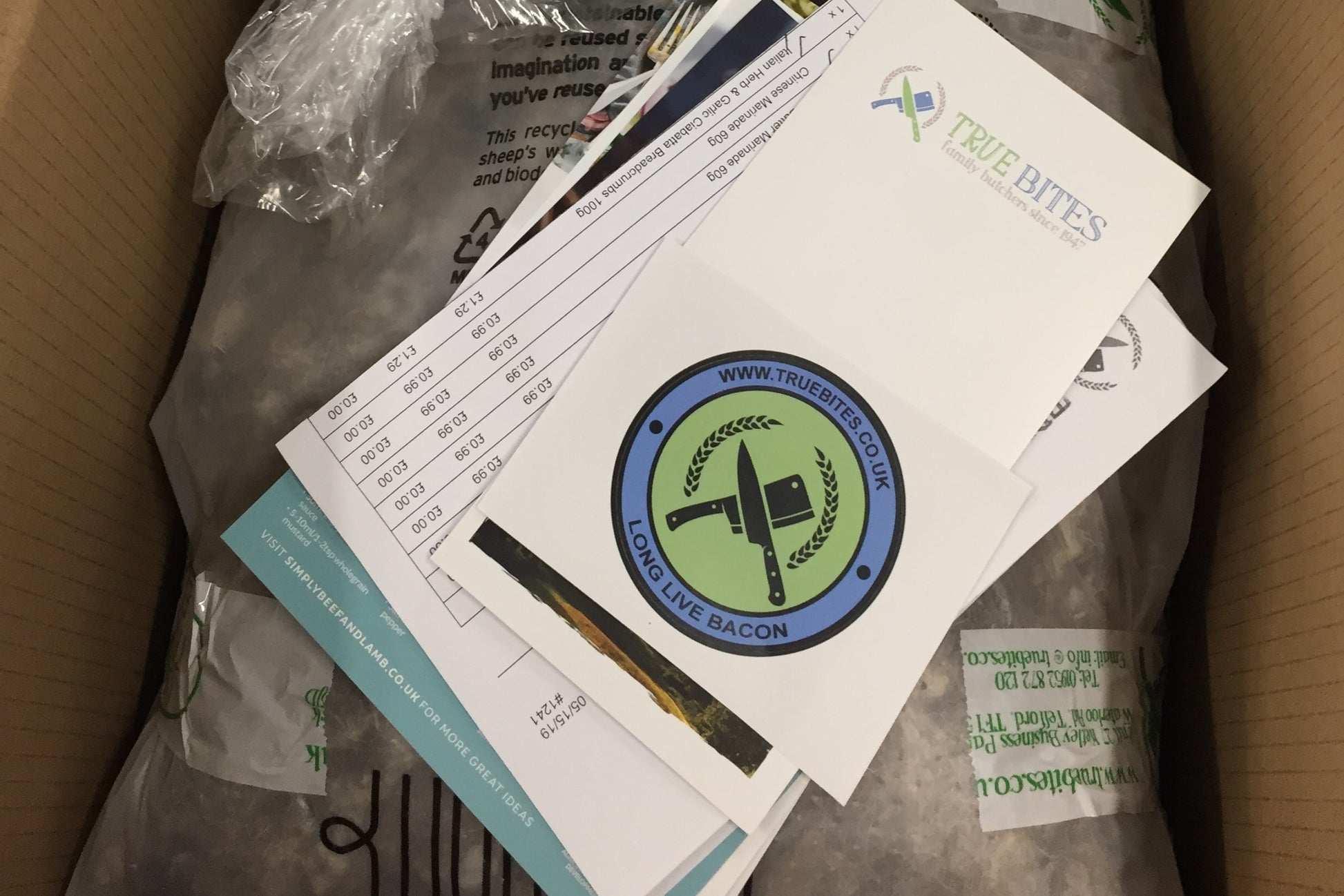 photo of a packaged monthly meat box with paperwork 