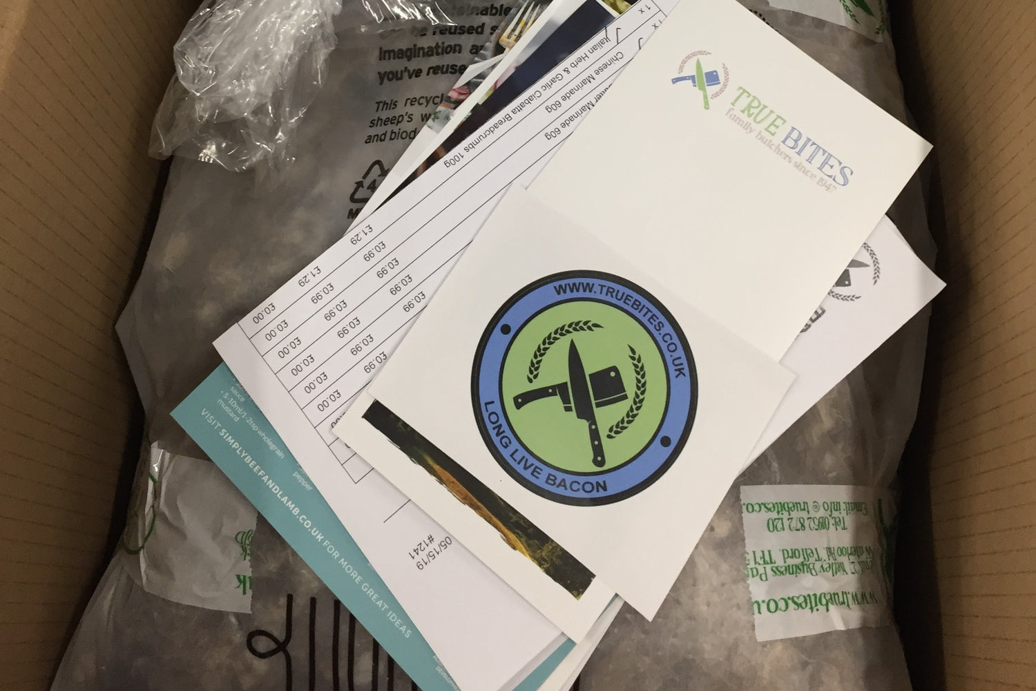 photo of a packaged monthly meat box with paperwork 