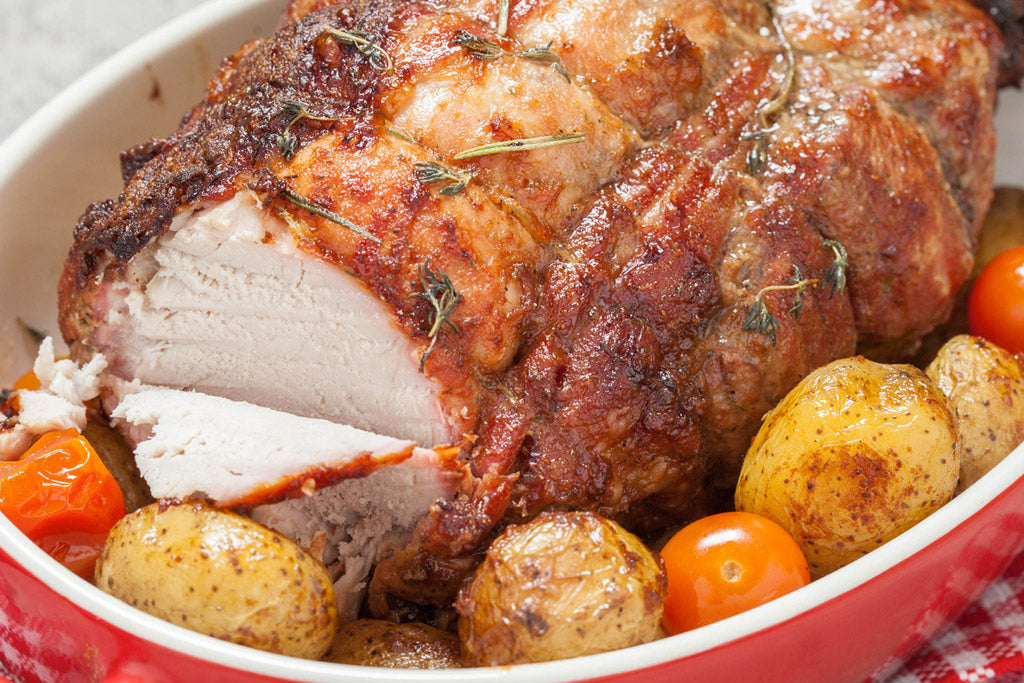 roasted pork loin in a dish with potatoes and tomatoes