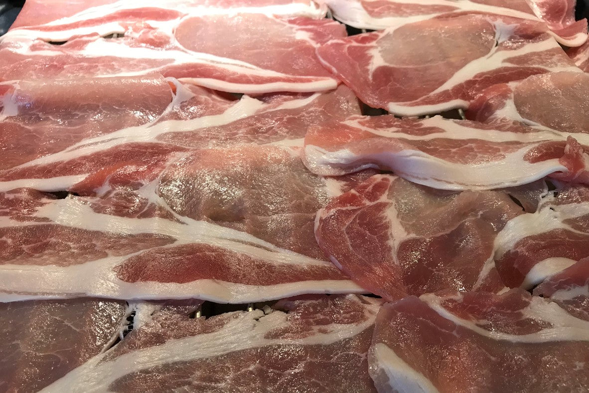 raw back bacon laid out on a rack ready for grilling