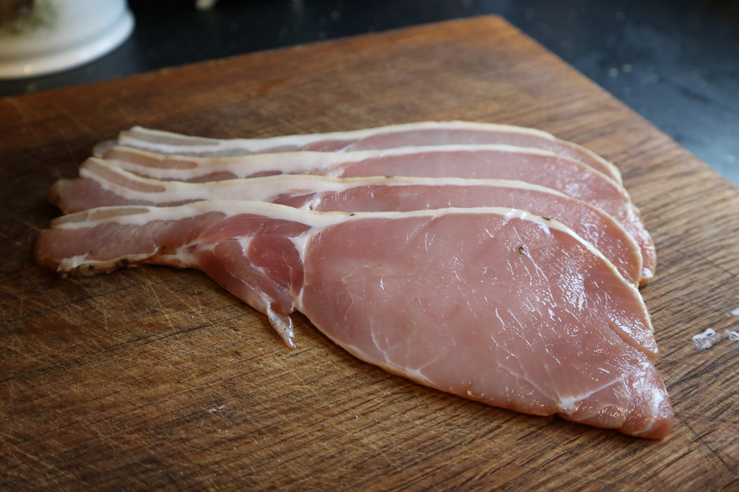 raw maple bacon on a wooden cutting board