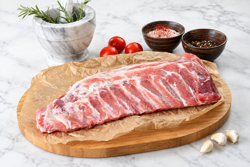 rack of raw pork belly ribs on butcher paper with cooking ingredients surrounding