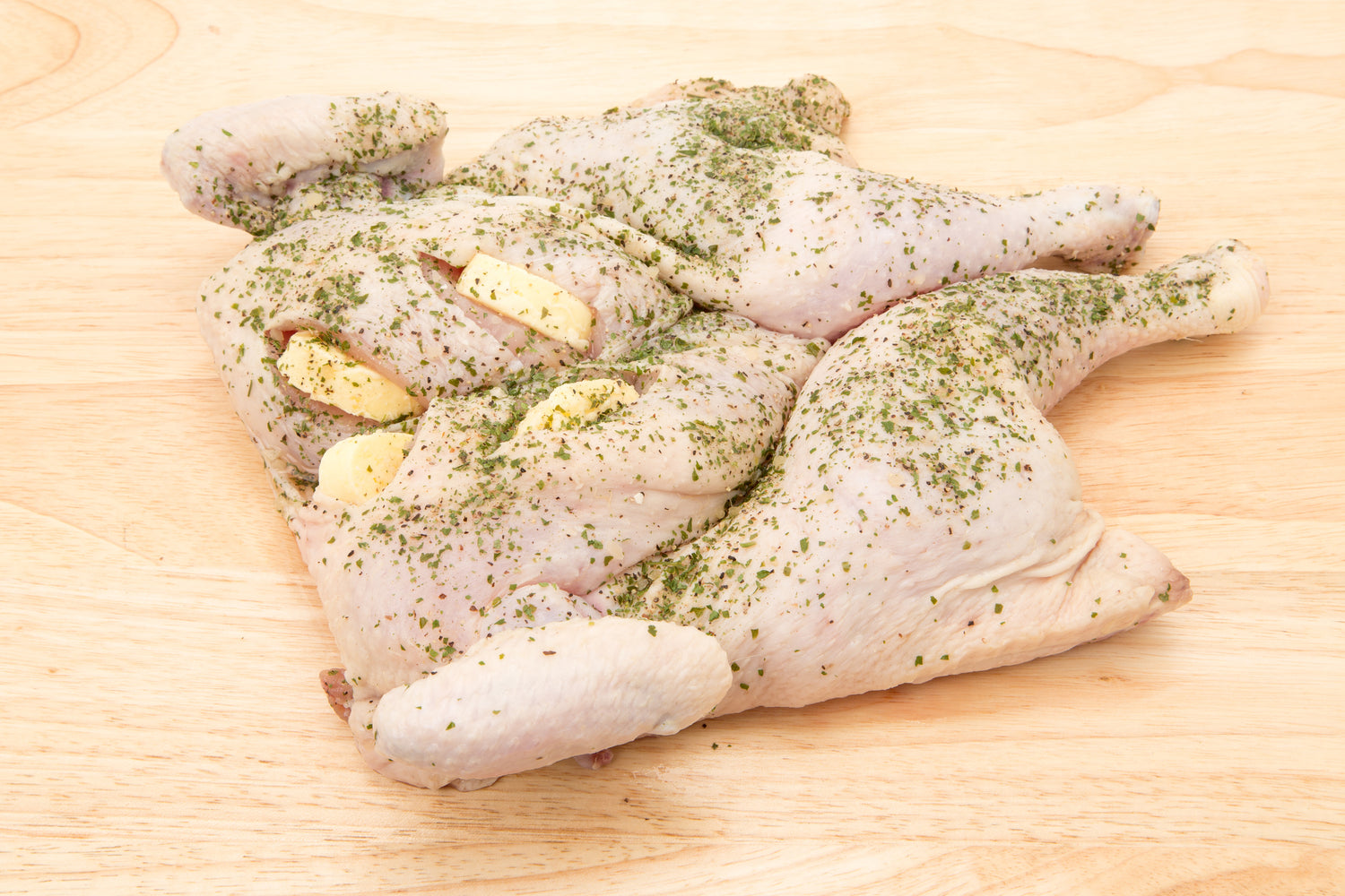 raw spatchcock chicken on a wooden board with herbs and butter