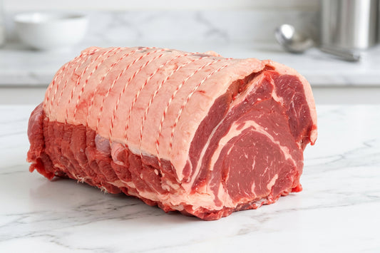 whole strung beef ribeye roasting joint on a wooden board.